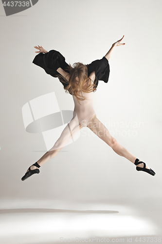 Image of Young beautiful dancer in beige swimsuit dancing on gray background