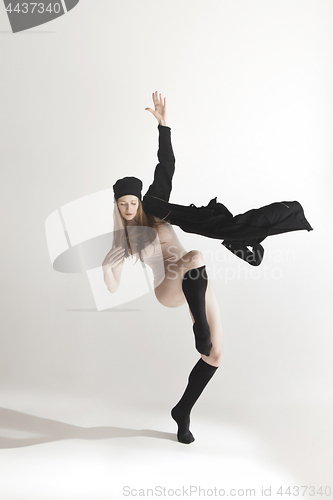 Image of Young beautiful dancer in beige swimsuit dancing on gray background