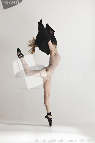 Image of Young beautiful dancer in beige swimsuit dancing on gray background