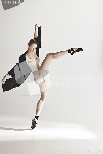 Image of Young beautiful dancer in beige swimsuit dancing on gray background