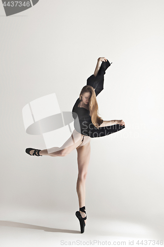 Image of Young beautiful dancer in beige swimsuit dancing on gray background