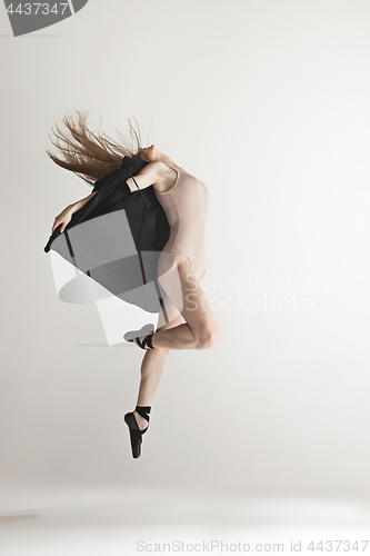 Image of Young beautiful dancer in beige swimsuit dancing on gray background