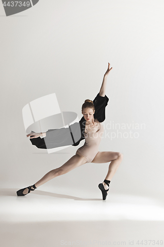 Image of Young beautiful dancer in beige swimsuit dancing on gray background