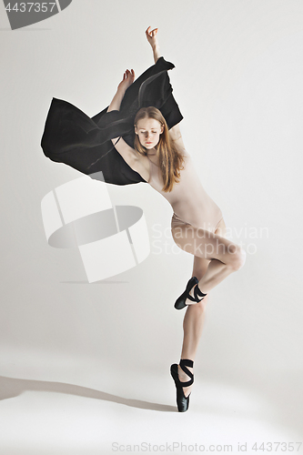 Image of Young beautiful dancer in beige swimsuit dancing on gray background