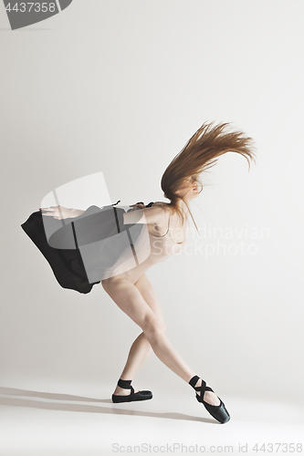 Image of Young beautiful dancer in beige swimsuit dancing on gray background