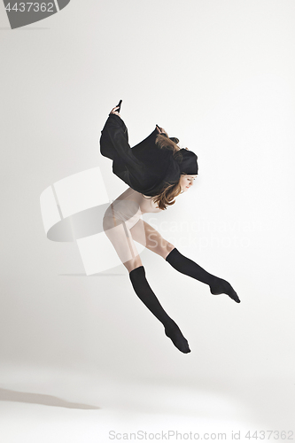 Image of Young beautiful dancer in beige swimsuit dancing on gray background