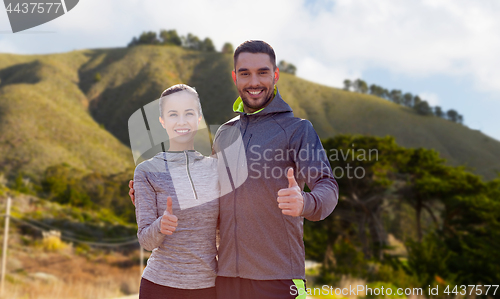 Image of smiling couple in sport clothes showing thumbs up