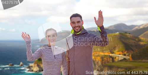 Image of smiling couple in sport clothes waving hand