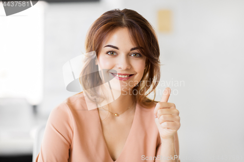 Image of portrait of smiling young woman showing thumbs up