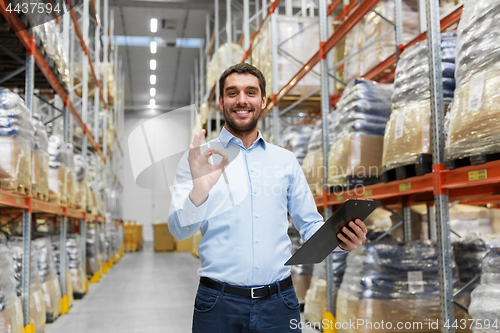 Image of businessman with clipboard at warehouse showing ok