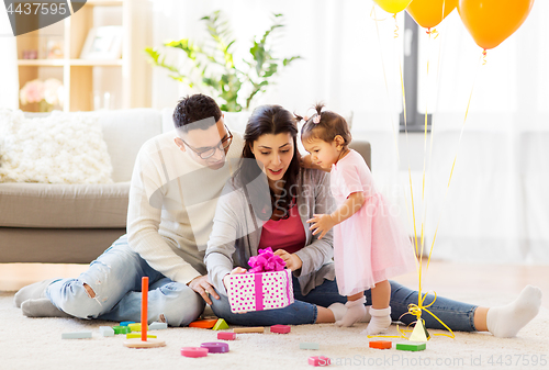 Image of baby girl with birthday gift and parents at home 