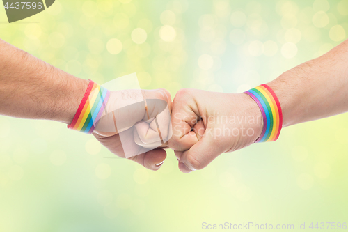 Image of hands with gay pride wristbands make fist bump