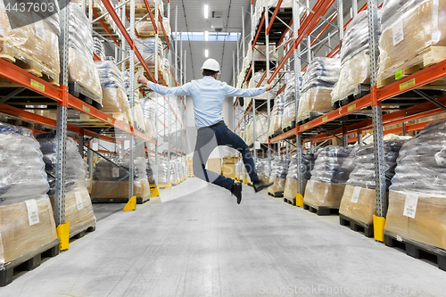 Image of happy businessman in helmet jumping at warehouse