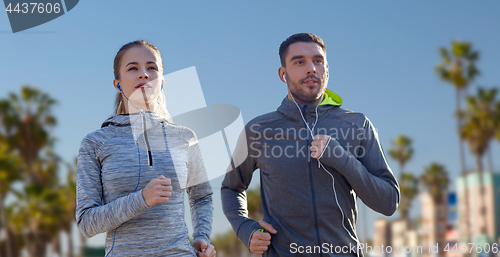 Image of couple with earphones running over venice beach