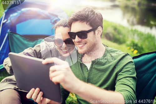 Image of happy couple with tablet pc at camping tent