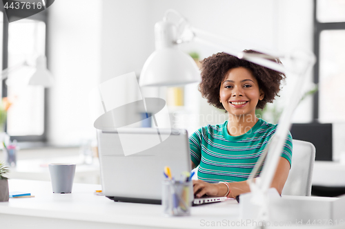 Image of happy african woman with laptop computer at office