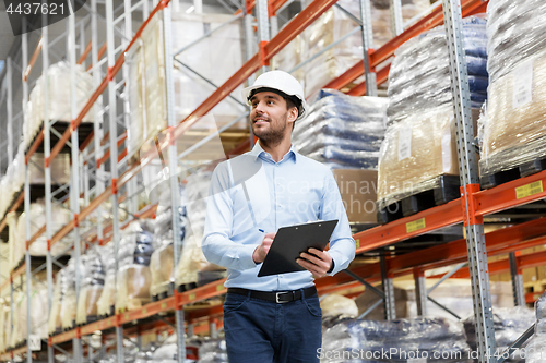 Image of businessman in helmet with clipboard at warehouse