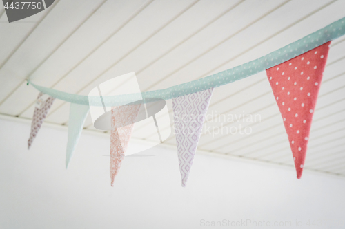 Image of Colorful birthday flags in pastel colors hanging from a ceiling