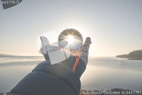 Image of Hand holding a crystal ball in the winter sunrise
