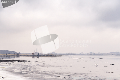 Image of Frozen lake by a city with industrial buildings