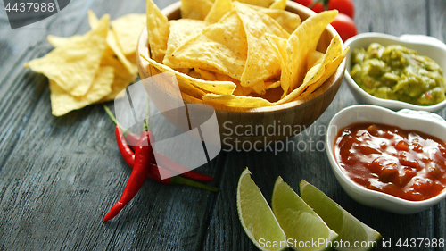 Image of Delicious nachos and sauces on table