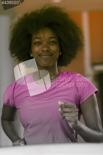 Image of afro american woman running on a treadmill