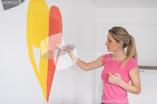 Image of woman painting a heart on the wall