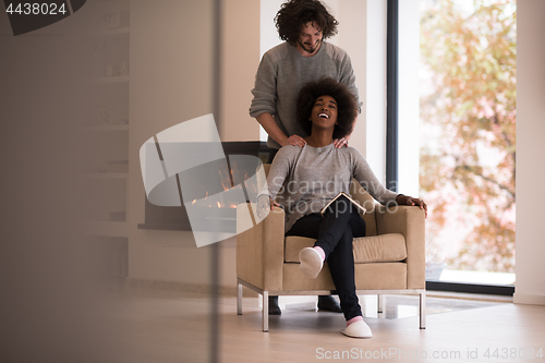 Image of multiethnic couple hugging in front of fireplace