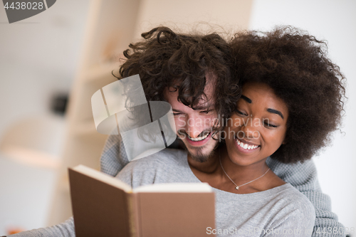 Image of multiethnic couple hugging in front of fireplace