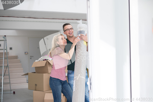 Image of couple carrying a carpet moving in to new home