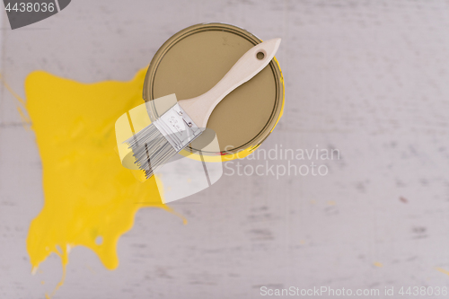 Image of Yellow paint tin can with brush on top