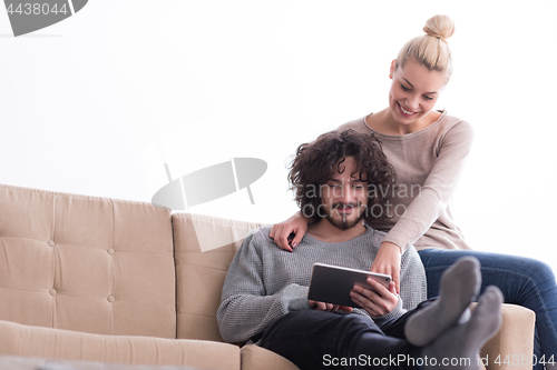 Image of couple relaxing at  home with tablet computers