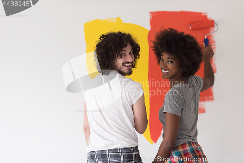 Image of multiethnic couple painting interior wall