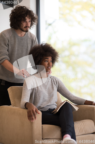 Image of multiethnic couple hugging in front of fireplace