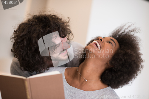 Image of multiethnic couple hugging in front of fireplace