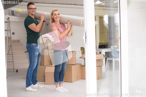 Image of couple carrying a carpet moving in to new home