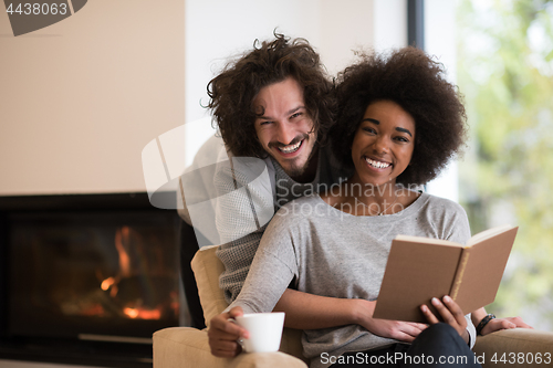 Image of multiethnic couple hugging in front of fireplace