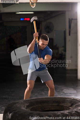 Image of man workout with hammer and tractor tire