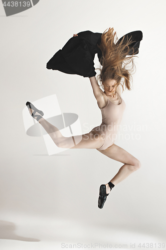 Image of Young beautiful dancer in beige swimsuit dancing on gray background