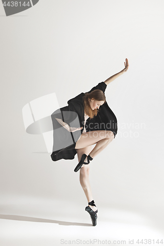 Image of Young beautiful dancer in beige swimsuit dancing on gray background