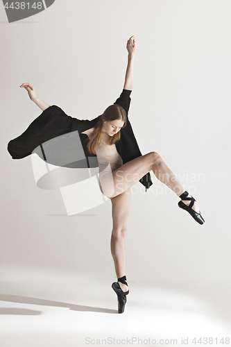 Image of Young beautiful dancer in beige swimsuit dancing on gray background