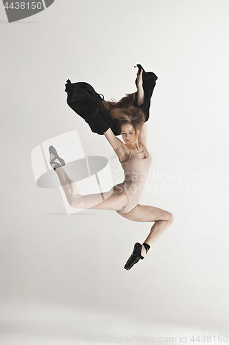 Image of Young beautiful dancer in beige swimsuit dancing on gray background