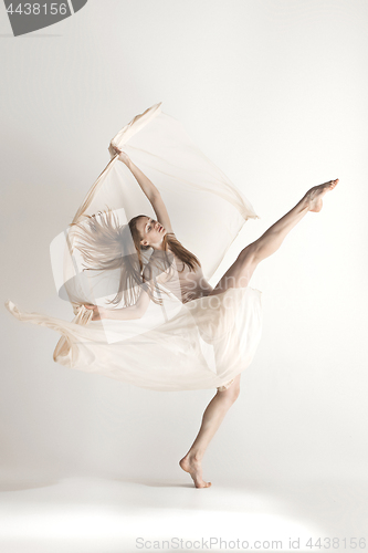 Image of Young beautiful dancer in beige swimsuit dancing on gray background