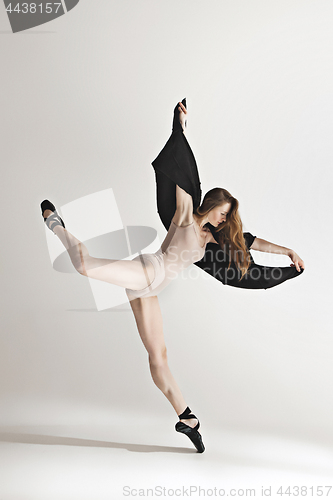 Image of Young beautiful dancer in beige swimsuit dancing on gray background