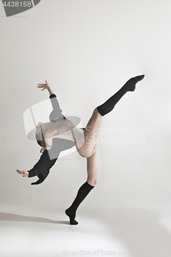 Image of Young beautiful dancer in beige swimsuit dancing on gray background