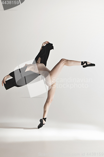 Image of Young beautiful dancer in beige swimsuit dancing on gray background