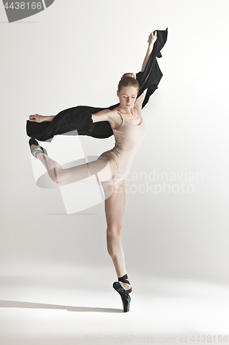 Image of Young beautiful dancer in beige swimsuit dancing on gray background