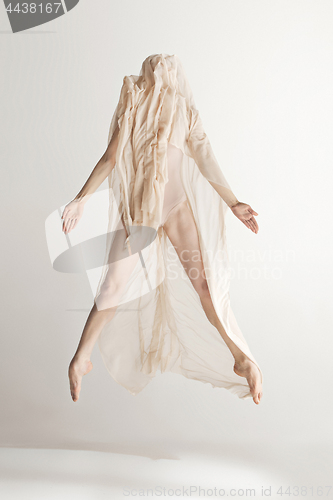 Image of Young beautiful dancer in beige swimsuit dancing on gray background