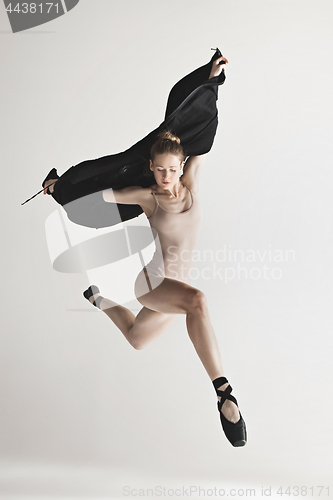 Image of Young beautiful dancer in beige swimsuit dancing on gray background