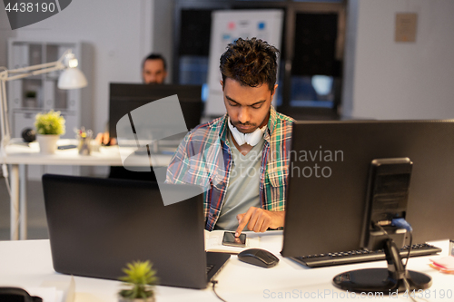 Image of creative man with smartphone at night office